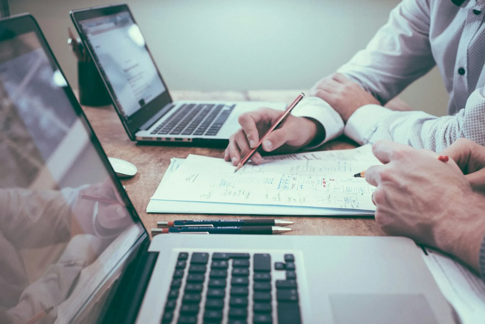 Consultants reviewing process diagrams and laptops at a desk